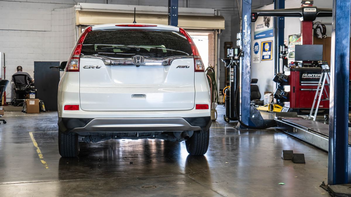 An SUV parked in an open service bay beside an alignment rack.